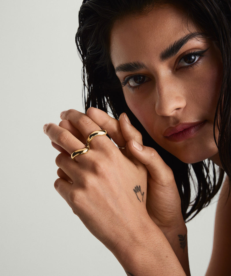 Mulher usando anel dourado com curvas